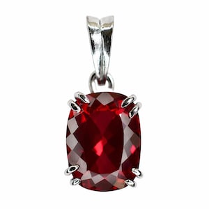 Op de afbeelding: Zilveren hanger met een grote, rechthoekige, gefacetteerde, dieprode edelsteen. De edelsteen wordt op zijn plaats gehouden door vier zilveren klauwen. De hanger heeft een zilveren balein voor een ketting.