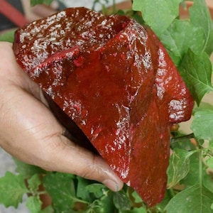Puede incluir: Una gran gema roja de forma irregular con un acabado brillante. La piedra tiene un color rojo intenso con toques de marrón y rosa.