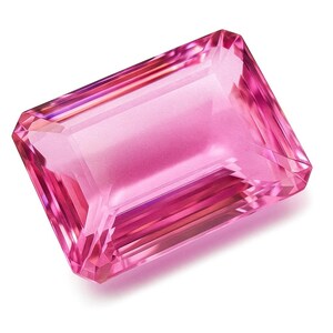 Puede incluir: Una gema rosa rectangular facetada. La gema tiene una apariencia translúcida, mostrando reflejos internos y una superficie pulida. El color varía de rosa claro a intenso, creando una exhibición vibrante.