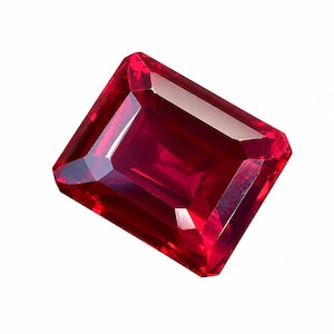 Puede incluir: Una gema de rubí facetada de corte rectangular. La gema es de color rojo intenso y saturado, con bordes limpios y afilados y un alto grado de claridad. La gema está aislada sobre un fondo blanco, resaltando su brillo.