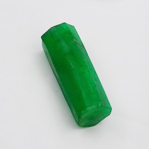 Op de afbeelding: Een heldergroene smaragd edelsteen met een gefacetteerde, zeshoekige vorm.