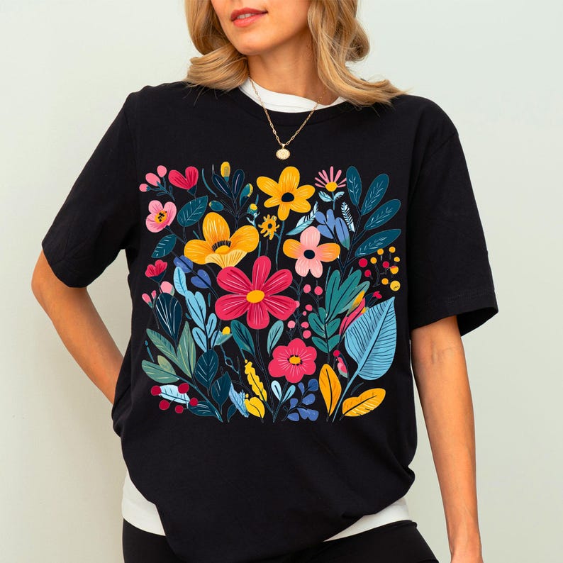 May include: Black t-shirt with a colourful floral print featuring yellow, red, pink, and blue flowers. The flowers are arranged in a bouquet-like design.
