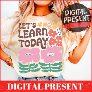Puede incluir: Una camiseta blanca con el texto "Let's Learn Today!" en letras marrones y diseños florales rosas y verdes.
