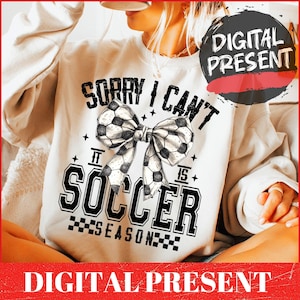 May include: White sweatshirt with a black and white graphic design that says "Sorry I can't it is soccer season" with a black and white soccer ball bow.