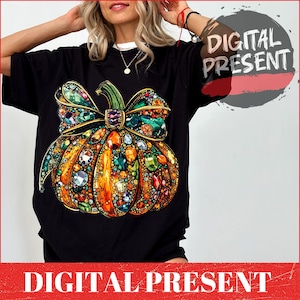 May include: Black t-shirt featuring a jeweled pumpkin design. The pumpkin is orange with a green stem and bow, adorned with colorful gems. The text "DIGITAL PRESENT" is visible in the image.