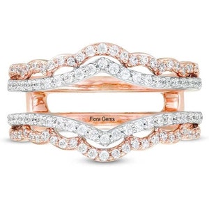Könnte beinhalten: Ein Ring-Setting aus Roségold und Weißgold mit einem zarten, wellenförmigen Design. Das Setting ist mit kleinen Diamanten besetzt und verfügt über eine zentrale Öffnung für einen Mittel-Stein.