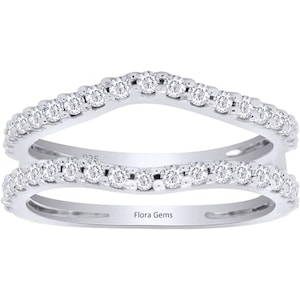 May include: A silver ring with a wave design, featuring a row of small diamonds on each side. The ring is engraved with the words "Flora Gems".