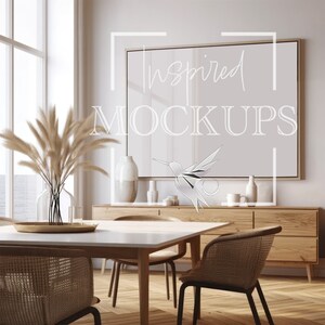 Puede incluir: Una mesa de comedor blanca con un marco de madera clara y cuatro sillas. La mesa est&aacute; puesta con una bandeja dorada y un jarr&oacute;n de hierba de la pampa seca. Una gran impresi&oacute;n enmarcada con el texto "Inspired Mockups" cuelga en la pared detr&aacute;s de la mesa.