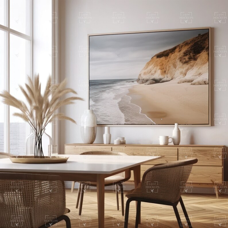 Puede incluir: Una mesa de comedor blanca con cuatro sillas, un aparador de madera y una gran impresi&oacute;n enmarcada de una escena de playa con un acantilado en el fondo. Las sillas est&aacute;n hechas de mimbre tejido y tienen patas de metal negro. La mesa tiene una tapa blanca y patas de madera. El aparador est&aacute; hecho de madera clara y tiene varios cajones y estantes. La impresi&oacute;n est&aacute; enmarcada en un marco de madera clara.