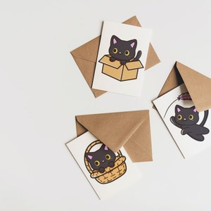 Puede incluir: Tres tarjetas de felicitaci&oacute;n con ilustraciones de gatos negros. Una tarjeta muestra un gato negro en una caja, otra muestra un gato negro en una cesta y la tercera muestra un gato negro jugando con una pluma.