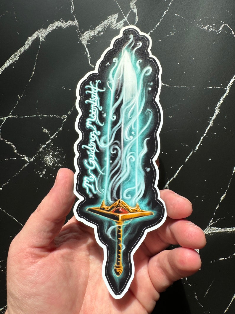 May include: A sticker of a glowing blue sword with a gold hilt and a red gem. The sword is surrounded by blue flames and the text "My Guiding Moonlight" is written on the side.