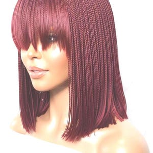 May include: A shoulder-length wig featuring fine, dark burgundy micro-braids throughout. The hair is styled in a straight, blunt cut with a full, straight-across fringe that covers the forehead, creating a uniform and sleek appearance.
