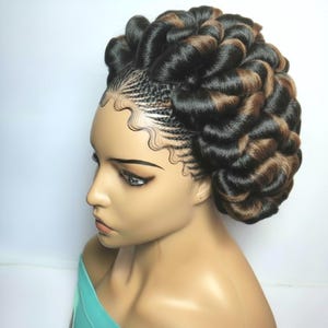 May include: A mannequin head with a complex hairstyle featuring cornrows and voluminous, spiraled sections of dark brown and light brown hair. The hair is styled in an updo, with intricate braiding and a polished finish. The mannequin is wearing a teal top.