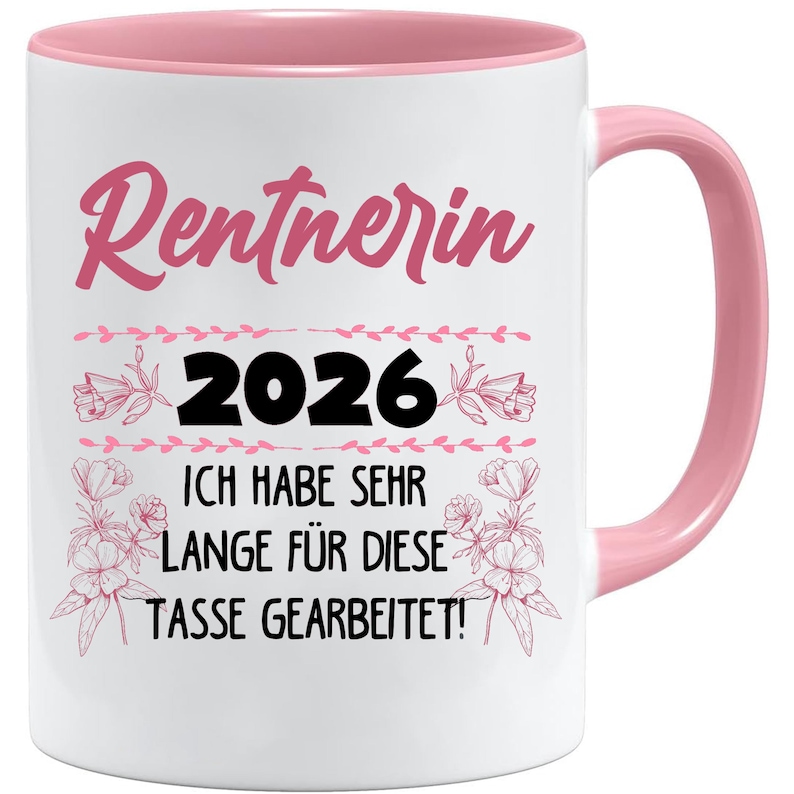 May include: White ceramic mug with a pink interior and handle. The mug features the word "Rentnerin" in pink script, the number "2026", and German text. Floral and leaf accents surround the text.
