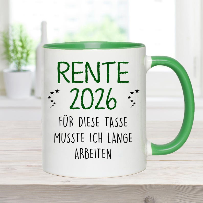 Pu&ograve; includere: Tazza in ceramica bianca con interno e manico verdi. La tazza presenta il testo "RENTE 2026" in verde, insieme alla frase "F&Uuml;R DIESE TASSE MUSSTE ICH LANGE ARBEITEN" in nero. Piccole stelle decorative.