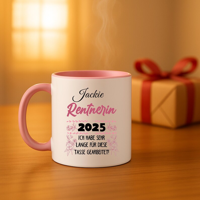 Puede incluir: Una taza de cer&aacute;mica blanca con asa e interior rosas. La taza presenta el nombre "Jackie" y la palabra "Rentnerin" en escritura rosa, junto con el a&ntilde;o "2025" y el texto alem&aacute;n "ICH HABE SEHR LANGE FUR DIESE TASSE GEARBEITET!"