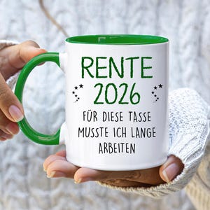 Pu&ograve; includere: Tazza in ceramica bianca con interno e manico verdi. La tazza presenta il testo "RENTE 2026" in verde, insieme alla frase "F&Uuml;R DIESE TASSE MUSSTE ICH LANGE ARBEITEN" in nero. Piccole stelle nere.