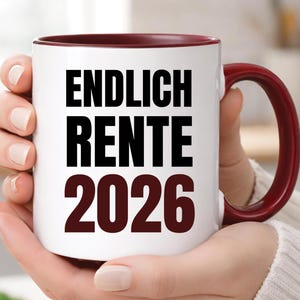 May include: White ceramic mug with a burgundy interior and handle. The mug features the text "ENDLICH RENTE 2026" in bold black and burgundy lettering. A perfect gift for someone looking forward to retirement.
