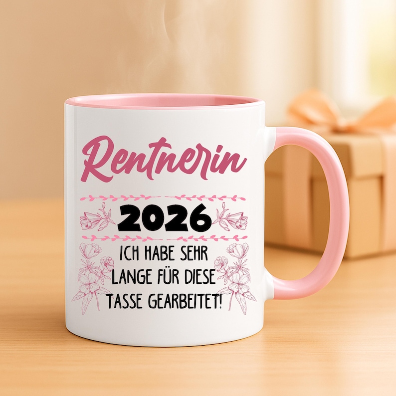 May include: White ceramic mug with a pink interior and handle. The mug features the word "Rentnerin" in pink script, the year "2026", and the German text "ICH HABE SEHR LANGE F&Uuml;R DIESE TASSE GEARBEITET!" in black. Floral accents decorate the design.