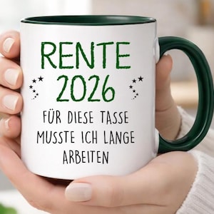 Pu&ograve; includere: Tazza in ceramica bianca con interno e manico verde scuro. La tazza presenta un testo verde che recita "RENTE 2026" sopra la frase "F&Uuml;R DIESE TASSE MUSSTE ICH LANGE ARBEITEN". Il design include piccoli accenti di stelle.