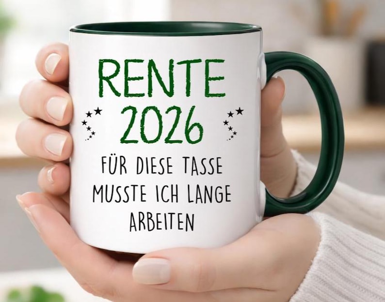 Pu&ograve; includere: Tazza in ceramica bianca con interno e manico verde scuro. La tazza presenta un testo verde che recita "RENTE 2026" sopra la frase "F&Uuml;R DIESE TASSE MUSSTE ICH LANGE ARBEITEN". Il design include piccoli accenti di stelle.