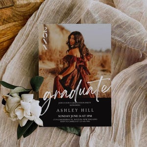 Op de afbeelding: Een zwart-witte uitnodiging voor een afstudeerfeest met een foto van een vrouw in een rode jurk. De tekst op de uitnodiging luidt "20XX graduate" en bevat de naam "Ashley Hill", de datum "Sunday June 24 at 3PM", het adres "17178 Gardenway Pl. Boston, New England" en de RSVP-informatie "RSVP to Camila at 123-456-7890".