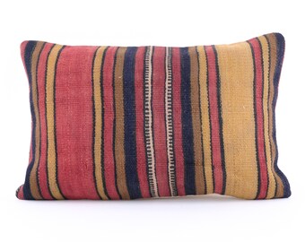 May include: A striped throw pillow with red, yellow, brown, and black stripes. The pillow is made of a woven fabric and has a rectangular shape.