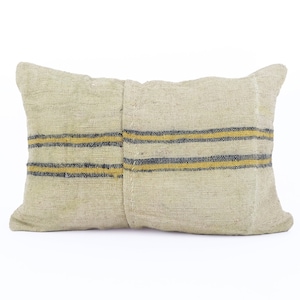 Puede incluir: Cojín rectangular beige con rayas horizontales negras y amarillas. El cojín tiene un aspecto texturizado y un diseño sencillo, adecuado para la decoración del hogar. El cojín probablemente está hecho de tela natural.