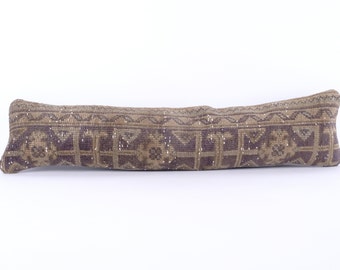 May include: A long, rectangular pillow with a brown and purple geometric pattern. The pillow is made of a woven fabric and has a fringed edge.