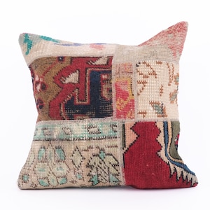 Puede incluir: Una almohada cuadrada con un diseño de patchwork. La almohada está hecha de diferentes piezas de tela en varios colores, incluyendo rojo, azul, verde y beige. La tela tiene una textura tejida y un aspecto vintage.