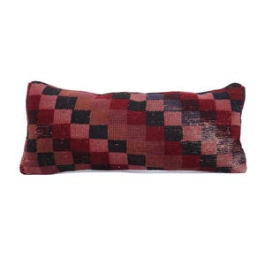 May include: Rectangular decorative pillow with a checkered pattern in shades of red, burgundy, and black. The pillow has a textured appearance and is likely made of woven fabric. The design is a classic, geometric style.