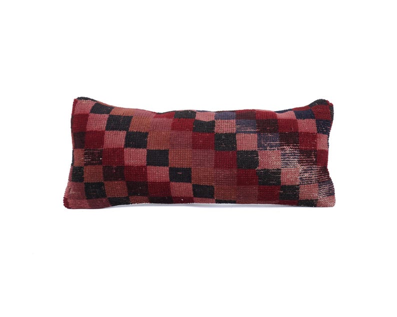 May include: Rectangular decorative pillow with a checkered pattern in shades of red, burgundy, and black. The pillow has a textured appearance and is likely made of woven fabric. The design is a classic, geometric style.
