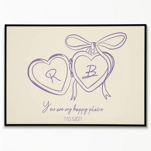 Puede incluir: Impresión enmarcada con un dibujo lineal morado de dos medallones en forma de corazón unidos por un lazo. El medallón izquierdo tiene la letra "R", y el derecho "B". El texto "You are my happy place" y la fecha "17.05.2021" están debajo.