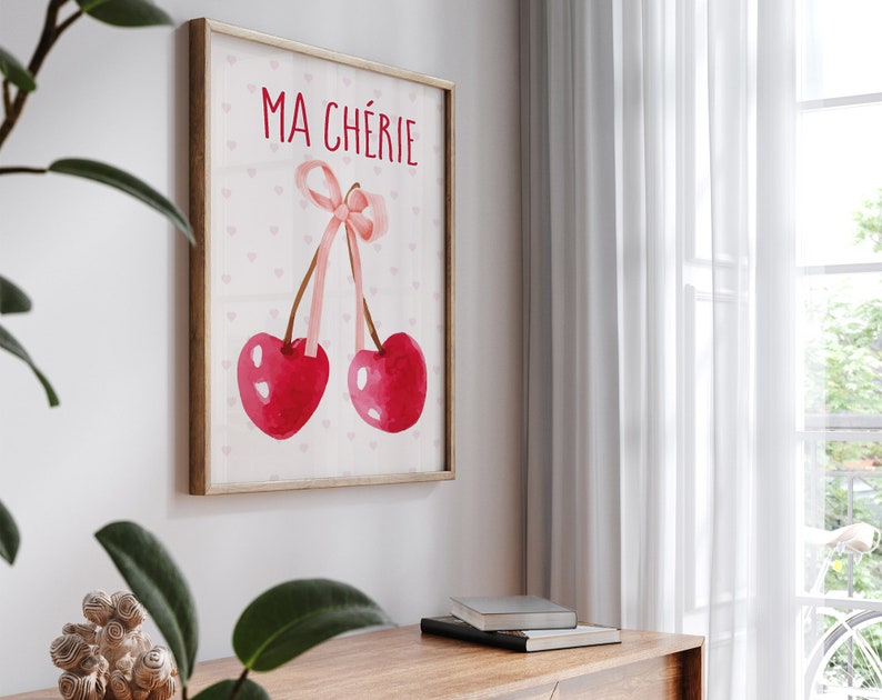 May include: A framed print with a pink background and white hearts. The print features two red cherries tied together with a pink ribbon. The text "MA CH&Eacute;RIE" is written in black at the top of the print.