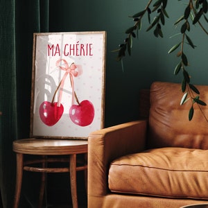 May include: A framed print with a watercolor illustration of two cherries with a pink ribbon bow. The text "MA CH&Eacute;RIE" is printed in red above the cherries.