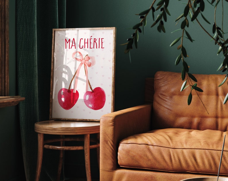 May include: A framed print with a watercolor illustration of two cherries with a pink ribbon bow. The text "MA CH&Eacute;RIE" is printed in red above the cherries.