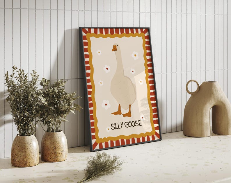 May include: A framed print with a white goose illustration on a cream background. The frame has a red and white striped border with a gold border. The text "Sally Goose" is printed in gold at the bottom of the print.