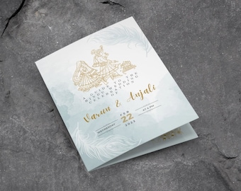 May include: A light blue wedding invitation with gold accents. The invitation features a traditional Indian couple in ornate clothing and a feather design. The text reads "A Guide to the Hindu Wedding Celebration of Varun & Anjali" and includes the date "Wednesday, February 22, 2023" and the time "At 4 PM".
