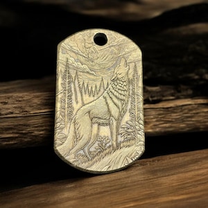 Peut inclure: Un porte-clés en laiton avec une image gravée détaillée d'un loup hurlant à la lune dans un décor de forêt.