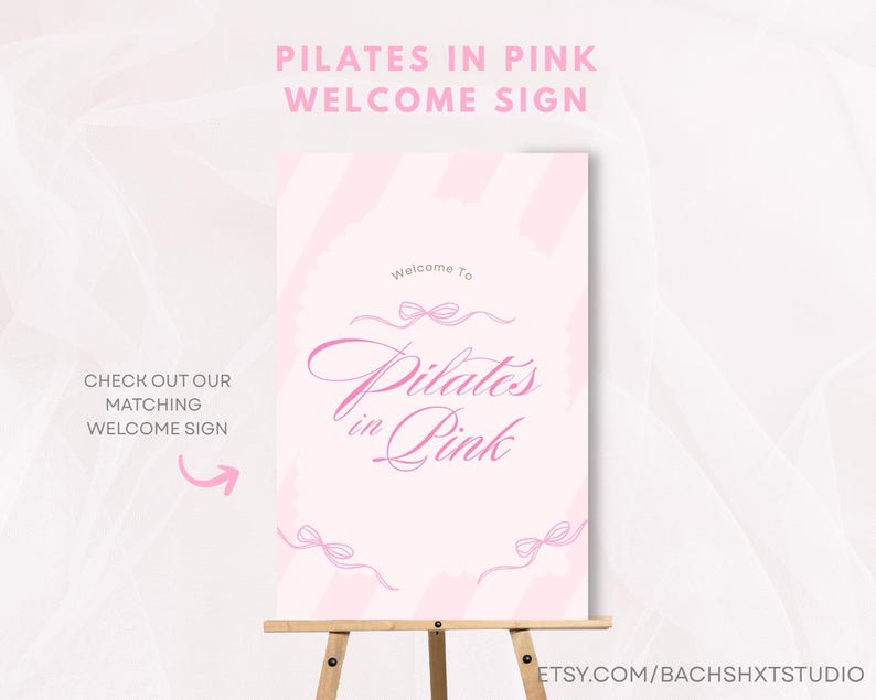 May include: A pink welcome sign on a wooden easel. The sign reads "Pilates in Pink" in elegant script, with decorative bows. The top of the sign says "Pilates in Pink Welcome Sign". The sign also says "Check out our matching welcome sign".