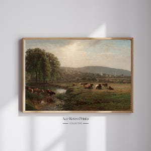 May include: A vintage painting depicting a pastoral scene with a stream running through a grassy field.  The painting features a group of cows grazing in the field, with a small village in the distance.  The sky is a soft blue with fluffy white clouds.