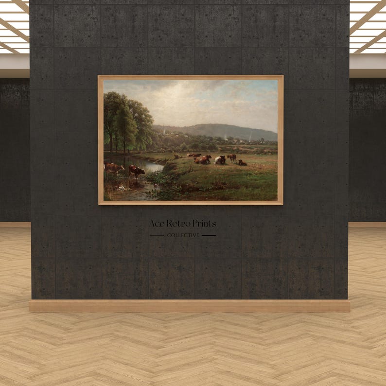 May include: A framed painting depicting a pastoral scene with a river, trees, and a herd of cattle grazing in a field. The painting is set against a backdrop of rolling hills and a distant town.
