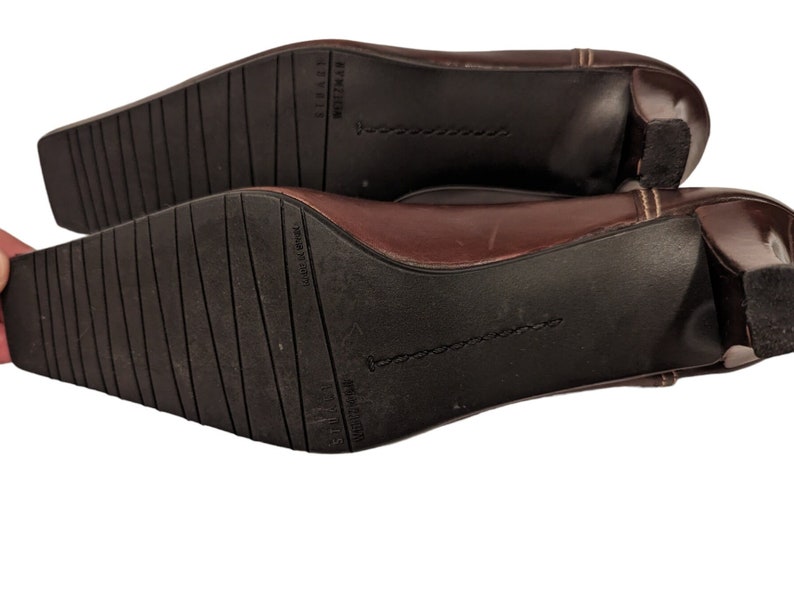 Pu&ograve; includere: Scarpe con tacco in pelle marrone con punta a punta e tacco piccolo. Le scarpe hanno una suola testurizzata e il nome del marchio "Nine West" &egrave; stampato sulla suola.