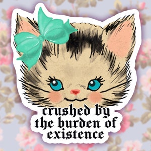 May include: A sticker featuring a cartoon kitten with a teal bow and the text "crushed by the burden of existence".
