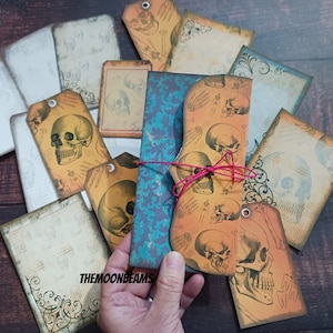 Może przedstawiać: Zestaw papierowych etykiet na Halloween w stylu vintage z różnymi wzorami czaszek. Etykiety są drukowane na teksturowanym papierze z efektem postarzenia i mają rustykalny, antyczny wygląd. Etykiety idealnie nadają się do dodania mrocznego akcentu do dekoracji na Halloween.