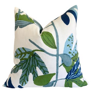 May include: A square cushion featuring a botanical design with green and blue leaves on a white background. The pillow is designed for home decor and adds a touch of nature to any room.