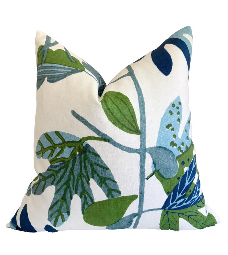 May include: A square cushion featuring a botanical design with green and blue leaves on a white background. The pillow is designed for home decor and adds a touch of nature to any room.