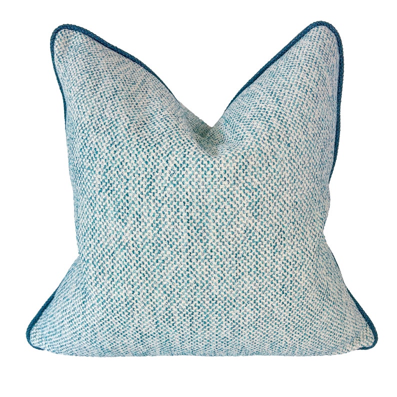 May include: A teal blue throw pillow with a white and teal patterned design. The pillow has a teal blue border.