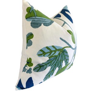 May include: A decorative cushion with a white backdrop and a botanical pattern in shades of blue and green. The cushion features large leaf and floral designs, adding a touch of nature-inspired decor to any living space. The cushion is a square shape.