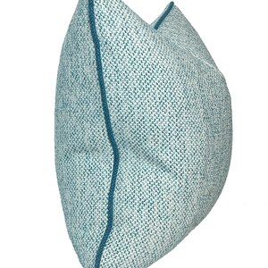 May include: A blue and white patterned throw pillow with a blue border. The pillow is made of a soft, textured fabric.